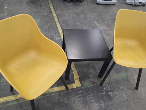 Gula plaststolar och svart kaffebord